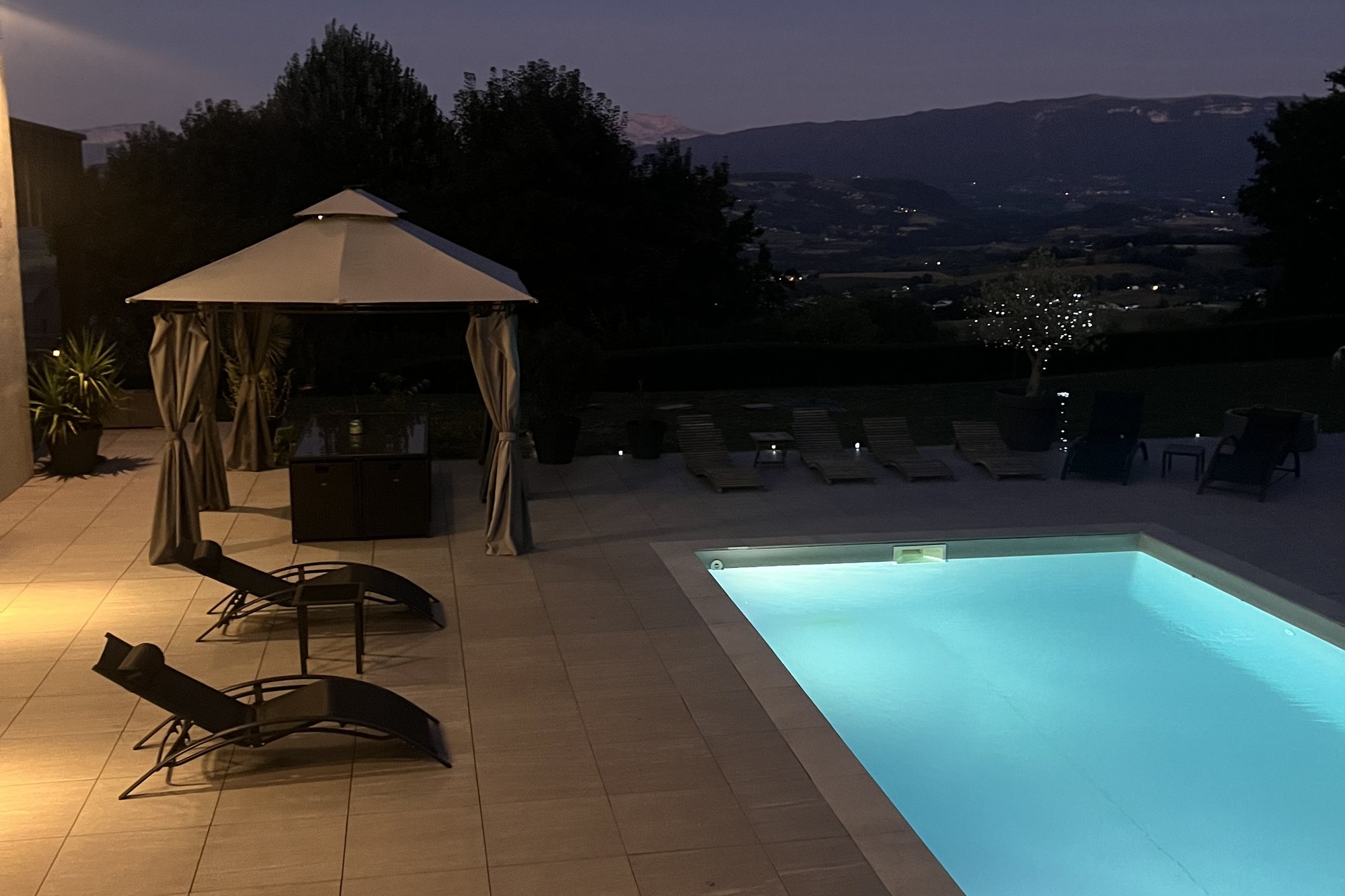 Piscine de nuit avec les lumières de la vallée en contrebas
